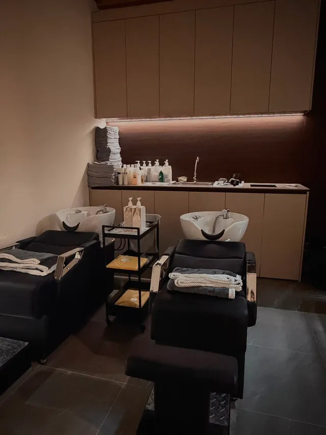 The wash area: two reclining basins in black, folded towels at the ready, and a low warm light along the counter.